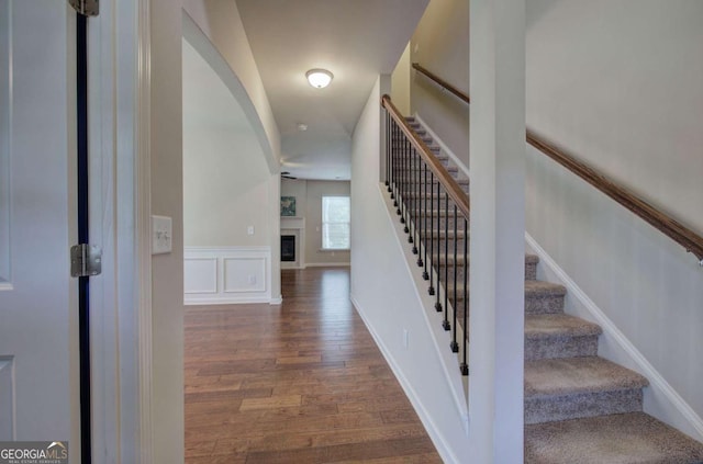 138 Gorham Gates Dr, Hiram, GA 30141 - staircase featuring wood finished floors, a wainscoted wall, arched walkways, a fireplace, and a decorative wall