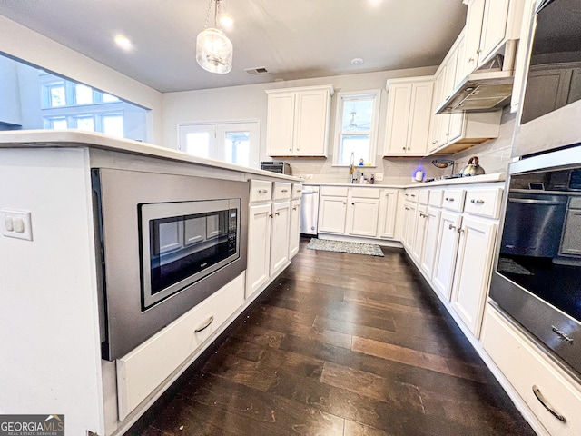 7860 Bristol Valley Dr, Cumming, GA 30028 - kitchen featuring appliances with stainless steel finishes, under cabinet range hood, white cabinetry, light countertops, and dark wood finished floors
