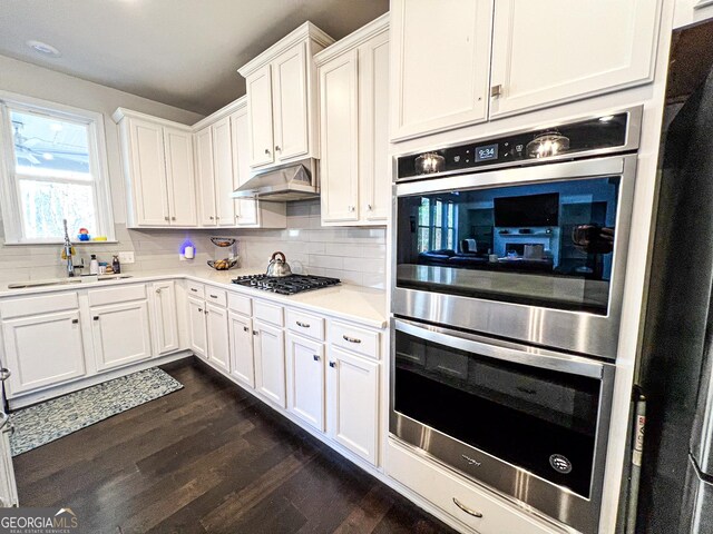 7860 Bristol Valley Dr, Cumming, GA 30028 - kitchen with under cabinet range hood, dark wood-type flooring, white cabinetry, and tasteful backsplash