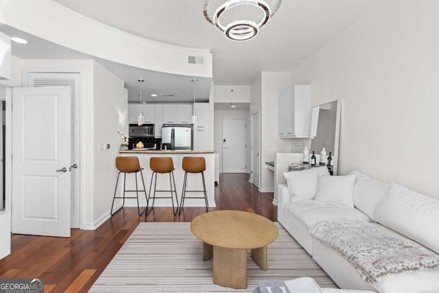 living room featuring wood finished floors, a chandelier, and baseboards