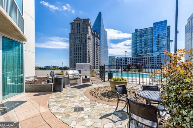 3324 Peachtree Rd NE Unit 1304, Atlanta, GA 30326 - view of patio / terrace featuring a city view, a community pool, fence, a grill, and exterior kitchen