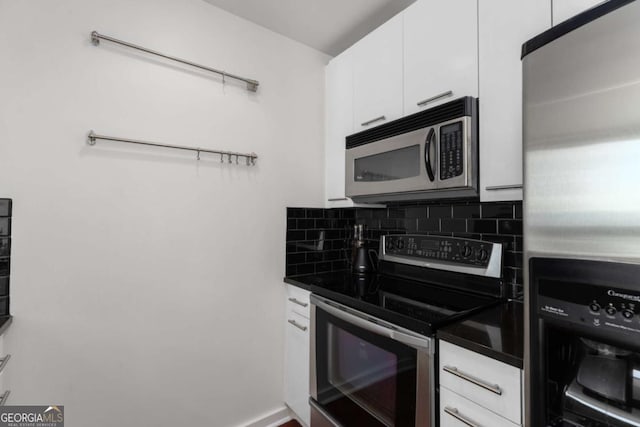 kitchen with stainless steel appliances, white cabinetry, decorative backsplash, and dark countertops