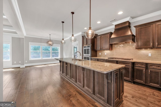 859 Heritage Lake Way, Grayson, GA 30017 - kitchen featuring custom range hood, stainless steel appliances, an island with sink, light stone counters, and dark wood-style flooring