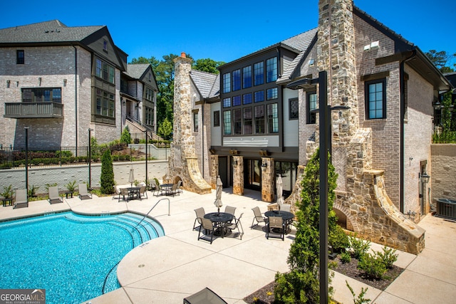 6790 Encore Blvd, Sandy Springs, GA 30328 - rear view of house featuring a chimney, a patio, stone siding, and a community pool