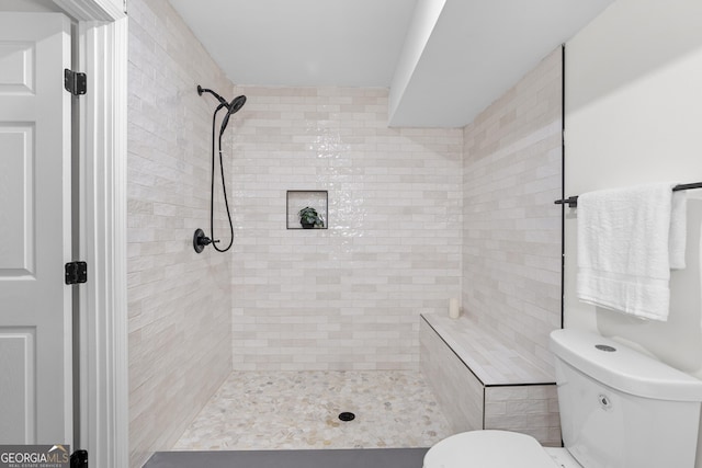 bathroom featuring toilet and a tile shower