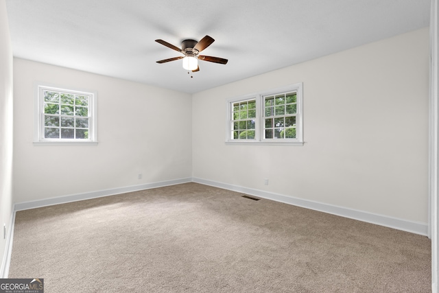 empty room featuring plenty of natural light, a ceiling fan, baseboards, and carpet
