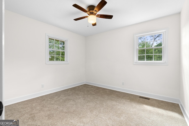 carpeted spare room with plenty of natural light, baseboards, and a ceiling fan