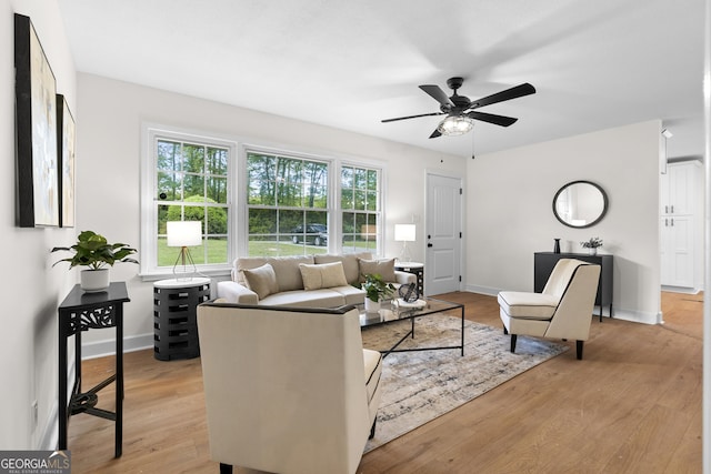 living room featuring light wood-style flooring, ceiling fan, and baseboards