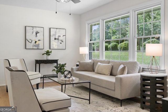 living room featuring light wood-type flooring, a ceiling fan, and baseboards