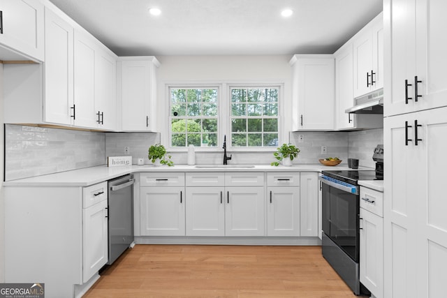 kitchen with a sink, electric stove, stainless steel dishwasher, under cabinet range hood, and recessed lighting