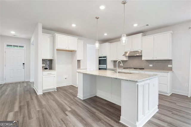 1809 Hanwoo Ln, Powder Springs, GA 30127 - kitchen with under cabinet range hood, light wood-type flooring, tasteful backsplash, and recessed lighting
