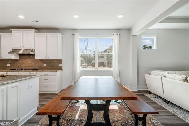 1809 Hanwoo Ln, Powder Springs, GA 30127 - kitchen with under cabinet range hood, gas stovetop, dark wood-style flooring, tasteful backsplash, and white cabinetry