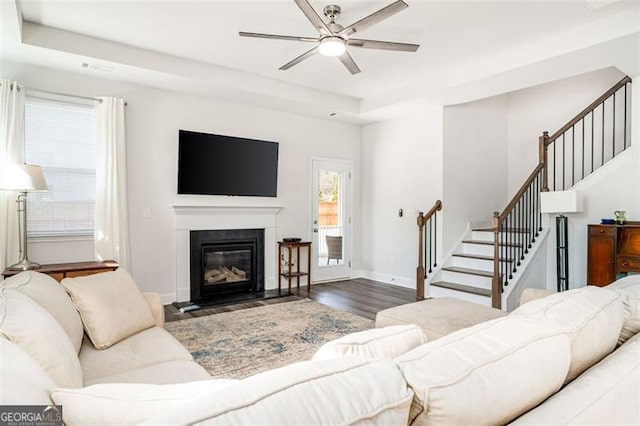 1809 Hanwoo Ln, Powder Springs, GA 30127 - living room with ceiling fan, stairway, wood finished floors, a fireplace with flush hearth, and a tray ceiling
