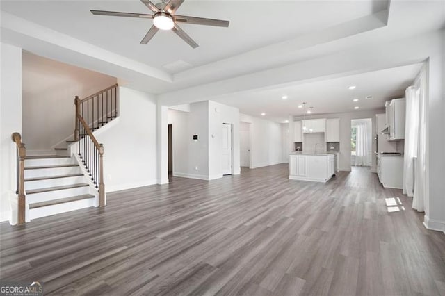 1809 Hanwoo Ln, Powder Springs, GA 30127 - unfurnished living room with ceiling fan, wood finished floors, a tray ceiling, recessed lighting, and baseboards