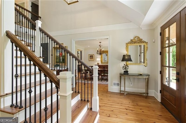 foyer entrance featuring a chandelier, wood finished floors, stairs, baseboards, and lofted ceiling