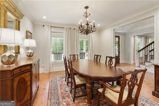 dining space featuring a chandelier, light wood-style floors, ornamental molding, baseboards, and stairway