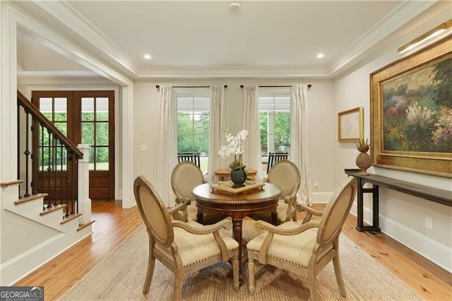 dining room featuring healthy amount of natural light, crown molding, light wood-style floors, and baseboards
