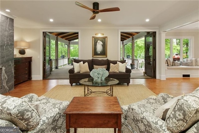 living room with crown molding, plenty of natural light, ceiling fan, wood finished floors, and baseboards