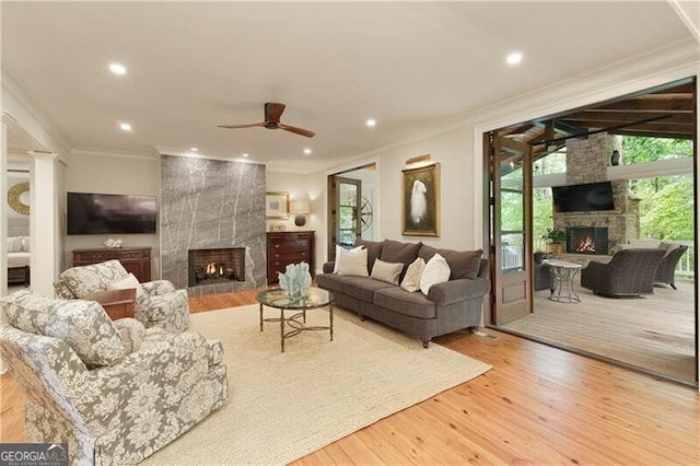 living area with a tiled fireplace, crown molding, ceiling fan, wood finished floors, and recessed lighting
