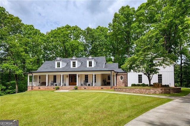 new england style home with covered porch, a front yard, board and batten siding, and a shingled roof