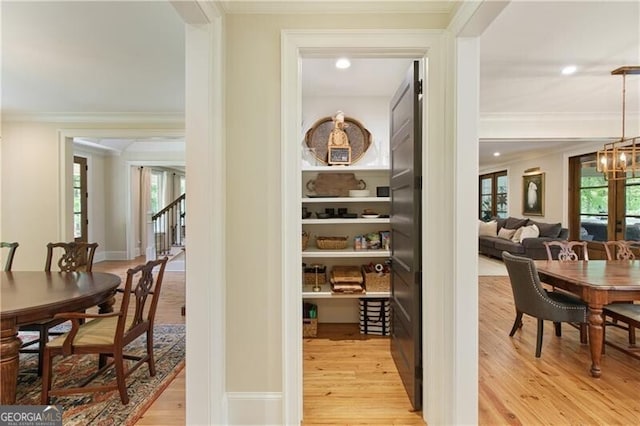 corridor featuring ornamental molding, light wood-type flooring, a chandelier, healthy amount of natural light, and recessed lighting