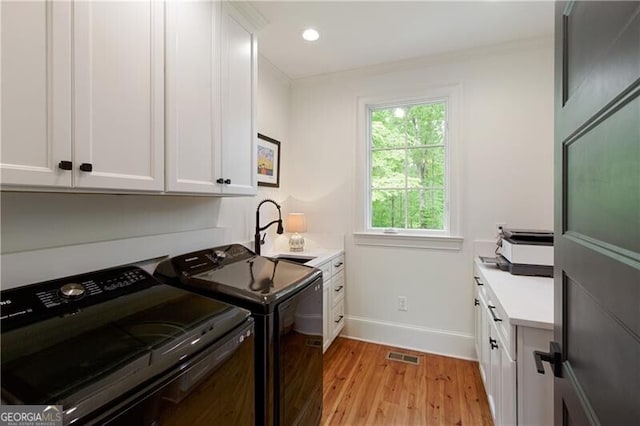laundry area featuring light wood finished floors, baseboards, cabinet space, separate washer and dryer, and an office area
