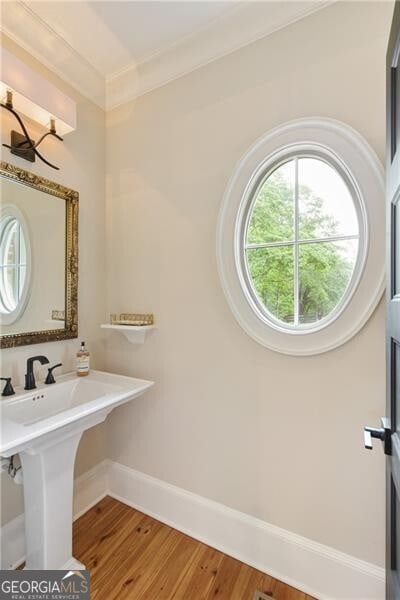 bathroom featuring baseboards, wood finished floors, and ornamental molding