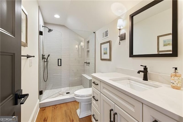 bathroom with toilet, a stall shower, wood finished floors, vanity, and lofted ceiling