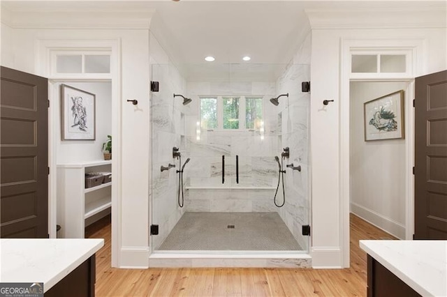 bathroom featuring a marble finish shower, vanity, wood finished floors, baseboards, and recessed lighting