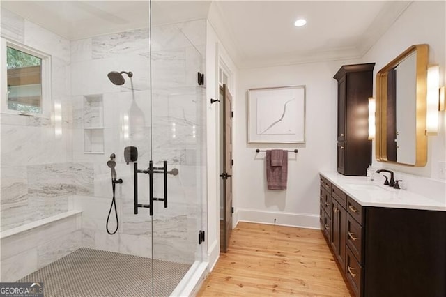 full bathroom featuring a marble finish shower, wood finished floors, vanity, baseboards, and ornamental molding