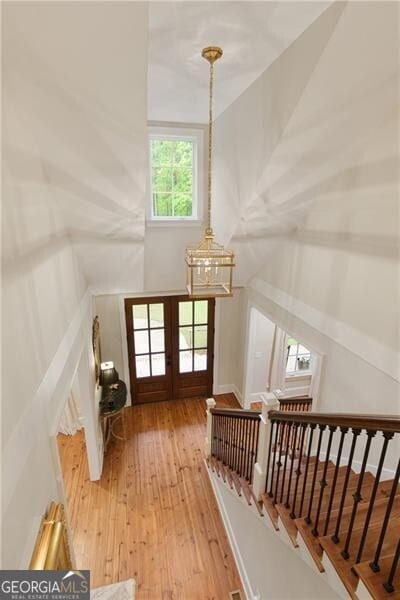 bonus room with hardwood / wood-style flooring, a chandelier, and french doors