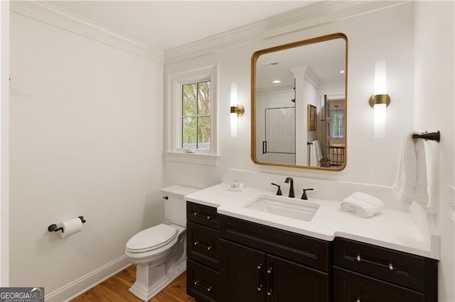 bathroom featuring toilet, wood finished floors, ornamental molding, baseboards, and vanity