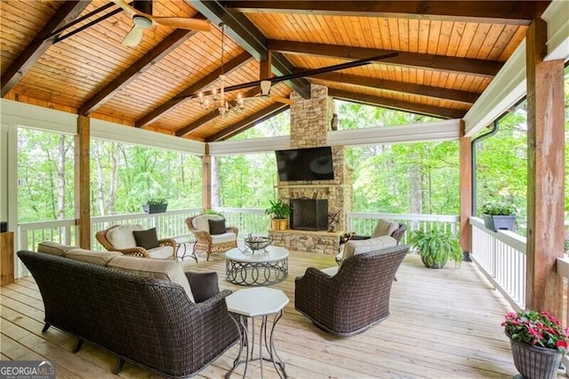 sunroom with a ceiling fan, an outdoor living space with a fireplace, and plenty of natural light