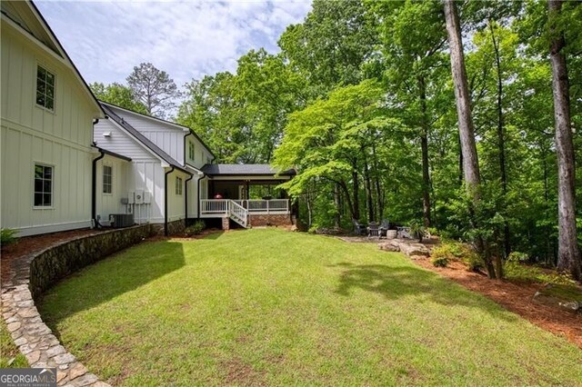 view of green lawn featuring a porch and central AC unit