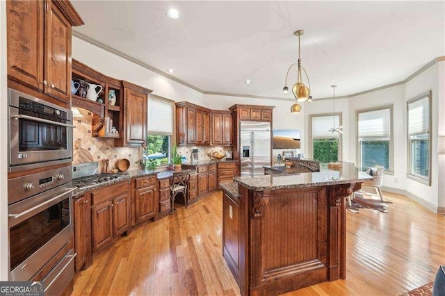 4162 Cumberland Point Dr, Gainesville, GA 30504 - kitchen featuring stainless steel appliances, crown molding, light wood finished floors, brown cabinets, and decorative backsplash