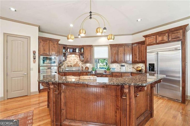 4162 Cumberland Point Dr, Gainesville, GA 30504 - kitchen with stainless steel appliances, a center island, light wood-type flooring, dark stone countertops, and crown molding