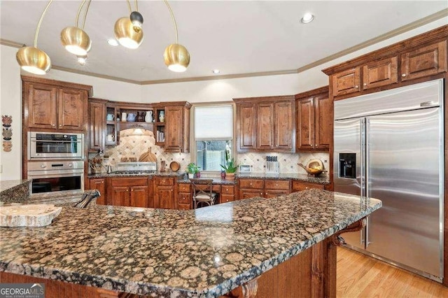 4162 Cumberland Point Dr, Gainesville, GA 30504 - kitchen with appliances with stainless steel finishes, brown cabinetry, decorative backsplash, and ornamental molding