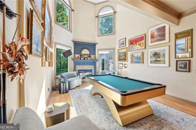 4162 Cumberland Point Dr, Gainesville, GA 30504 - recreation room featuring wood finished floors, billiards, a stone fireplace, ornamental molding, and a towering ceiling