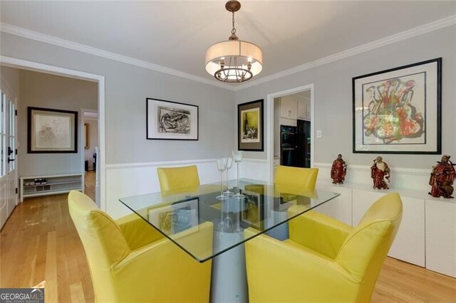 dining space featuring light wood finished floors, a chandelier, and ornamental molding
