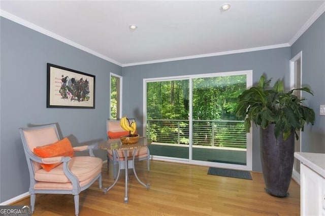 sitting room featuring light wood-style flooring, crown molding, and baseboards