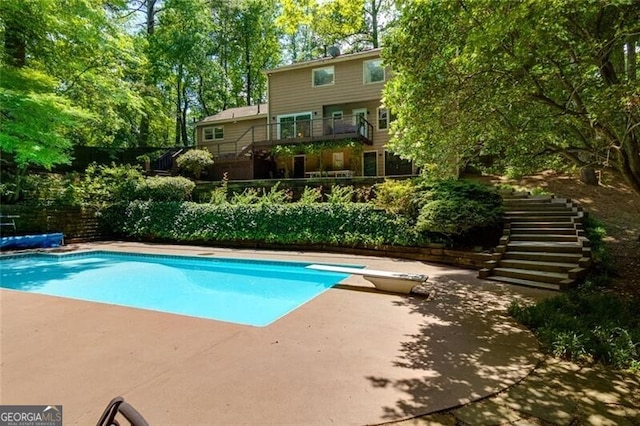 view of pool featuring stairs, a diving board, a patio area, and fence