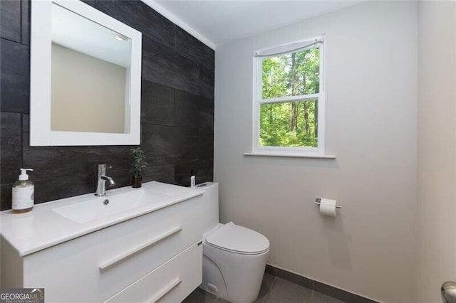 bathroom featuring toilet, vanity, tile patterned floors, decorative backsplash, and baseboards