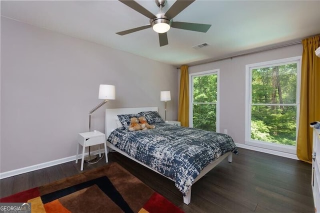 bedroom with wood finished floors, multiple windows, baseboards, and ceiling fan