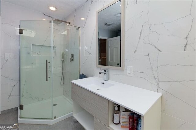 full bath featuring a marble finish shower and vanity