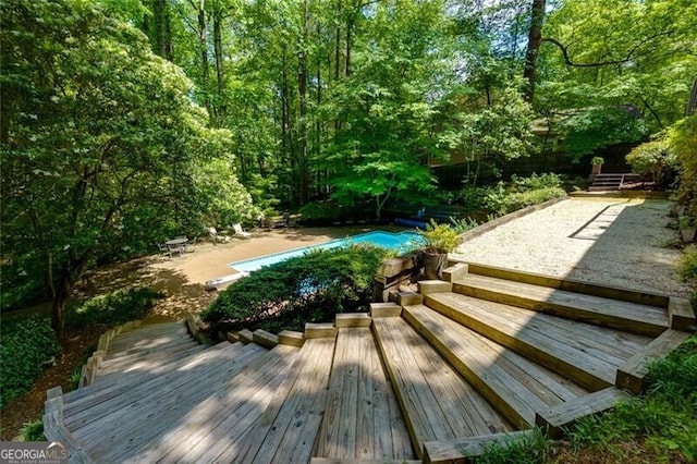 swimming pool with a wooden deck and a patio
