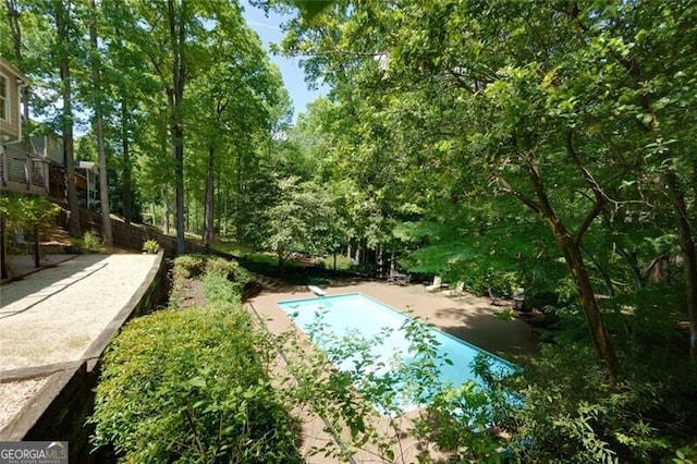 swimming pool with a diving board and a patio area