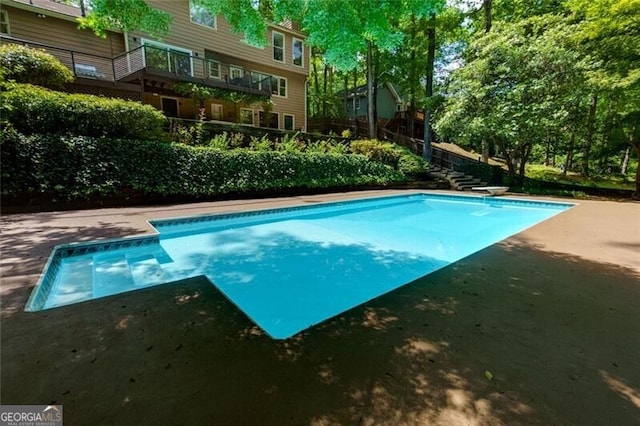 view of swimming pool featuring a diving board