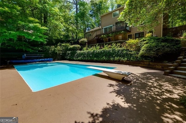 view of pool with a patio and a diving board