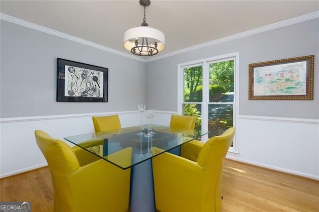 dining area with light wood-style floors, ornamental molding, and a chandelier