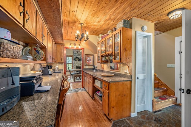 259 Eagle Chase Cir, Dillard, GA 30537 - kitchen featuring wooden ceiling, brown cabinetry, a chandelier, dark countertops, and glass insert cabinets
